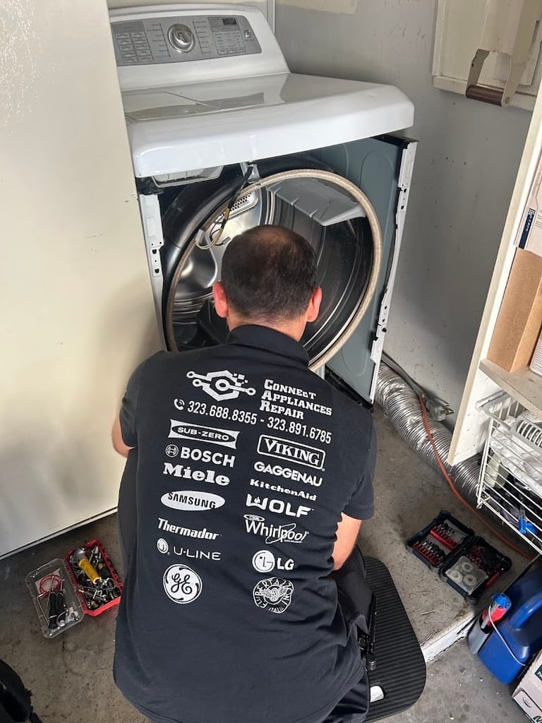 Appliance repair technician servicing a dryer, viewed from behind while working on the machines interior