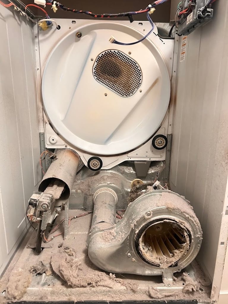 Interior view of an open washing machine showing lint trap, drum, and dusty ventilation ducts