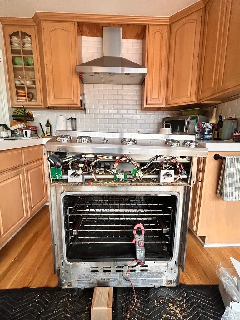 Disassembled kitchen stove revealing internal components and wiring during repair or replacement.